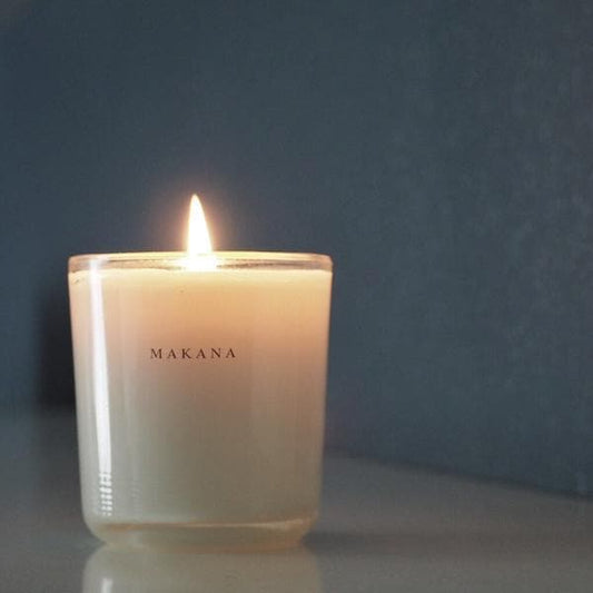 A clear glass jar candle with white wax and a white square label that reads, "Coconut Milk Makana" in clean black text.