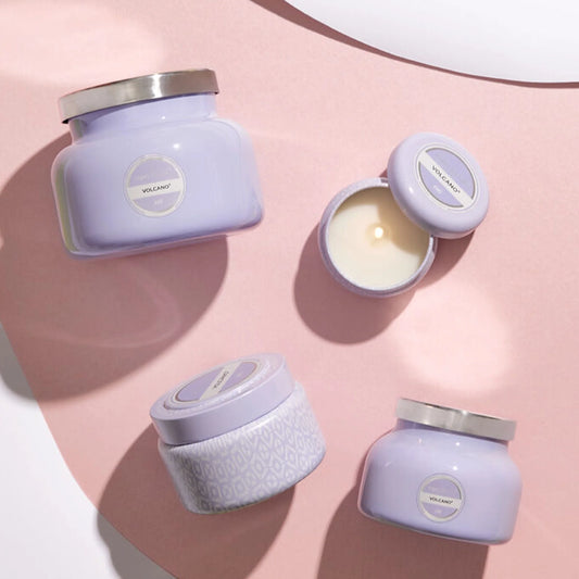 Four different sized and shaped glass candle jars in a lavender purple color. Each has a circular label that reads, "Volcano".